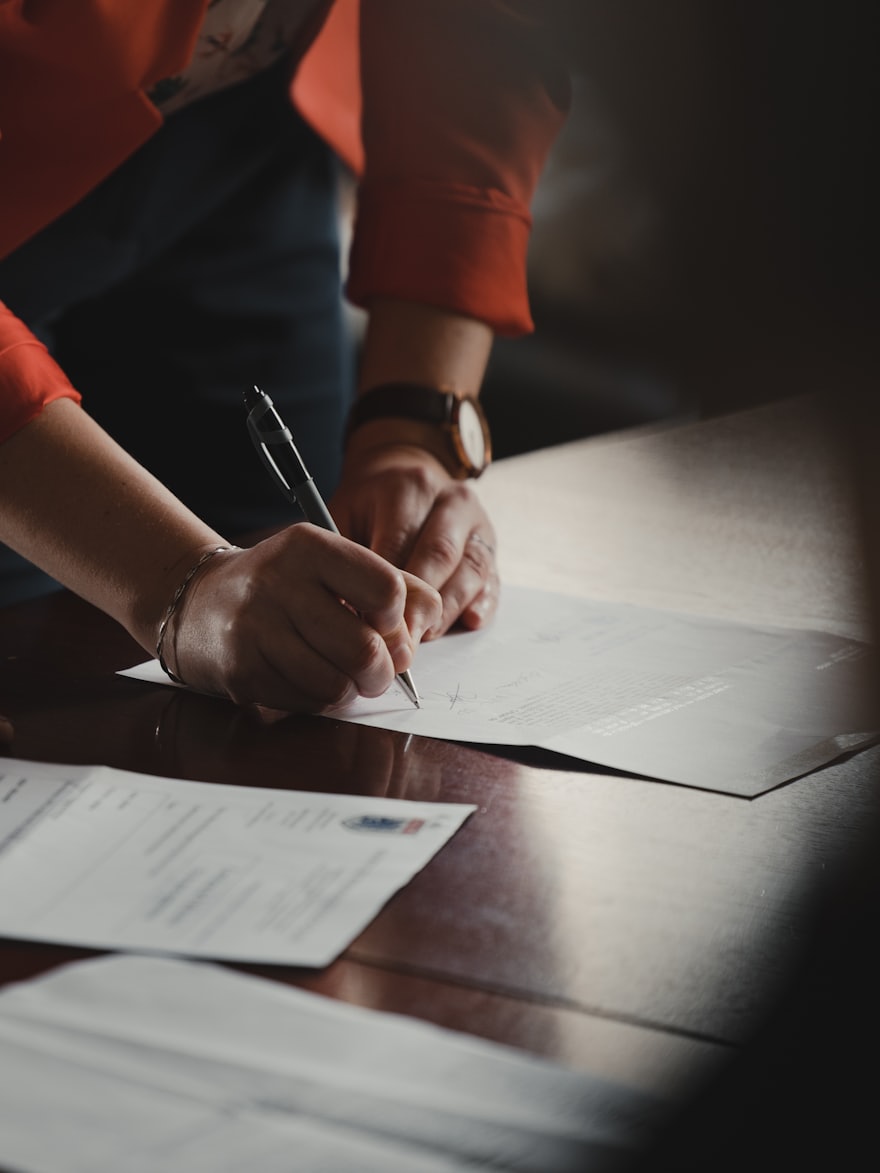 A person signing a document at a desk