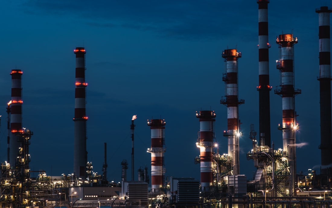 Refinery towers lit against a deep blue evening sky