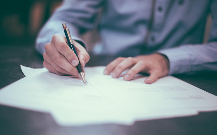 A hand writing on a document with a fountain pen